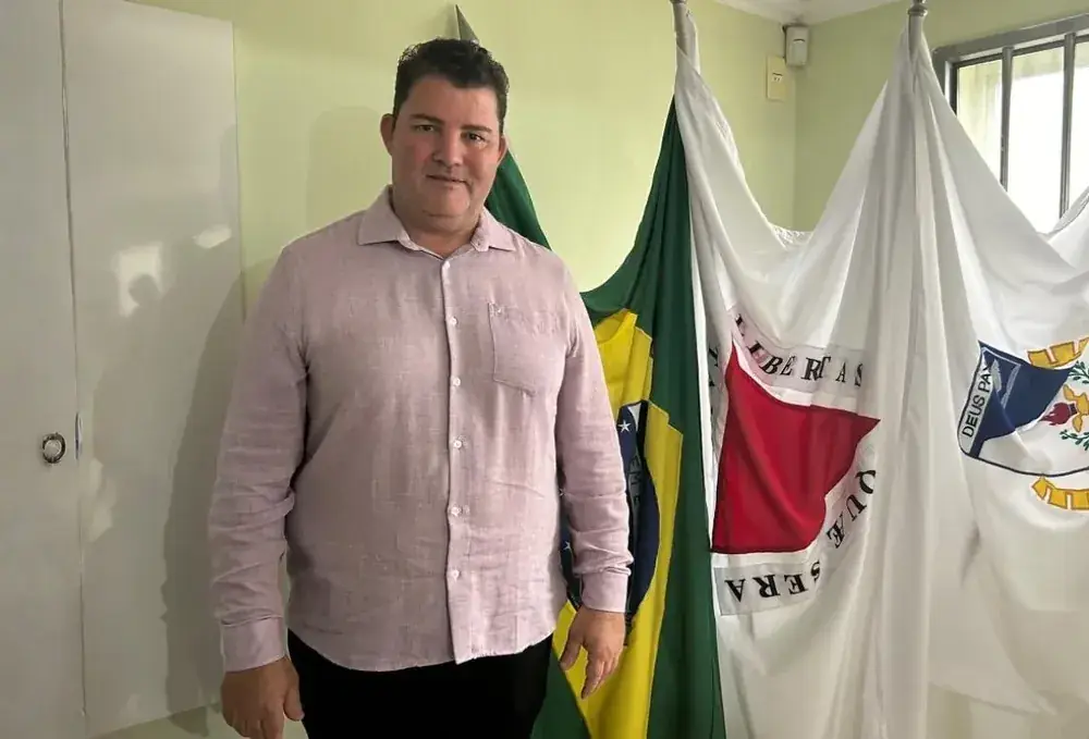 Márcio Lima no gabinete, ao lado das bandeiras do Brasil e de Minas Gerais